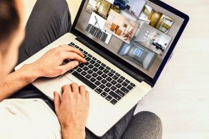 Home buyer looks for a home online on his laptop by comparing modalities in the pictures taken of each property. 